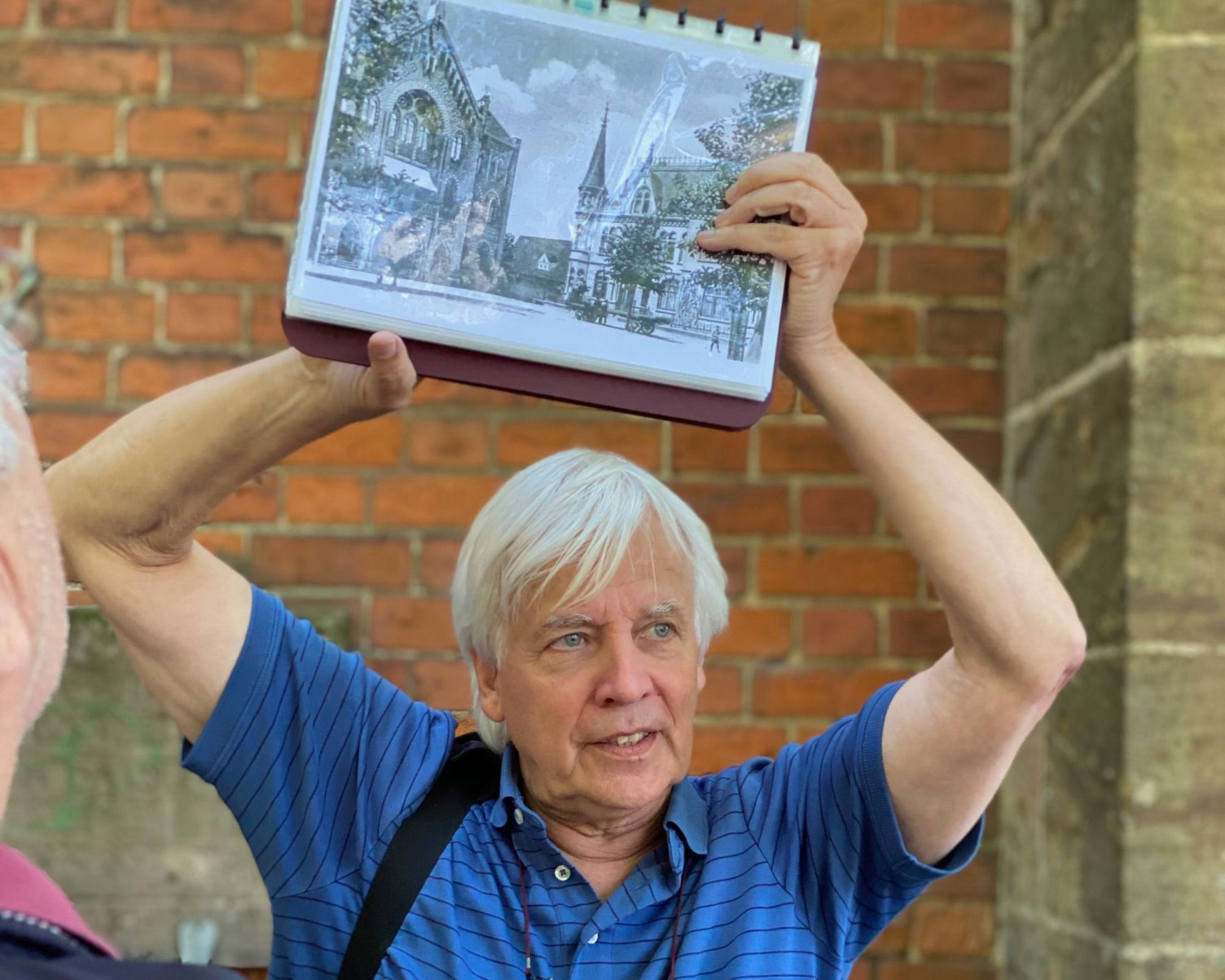 Dr. Johannes Schnepel-Boomgaarden hält bei einer Führung ein Bild hoch.